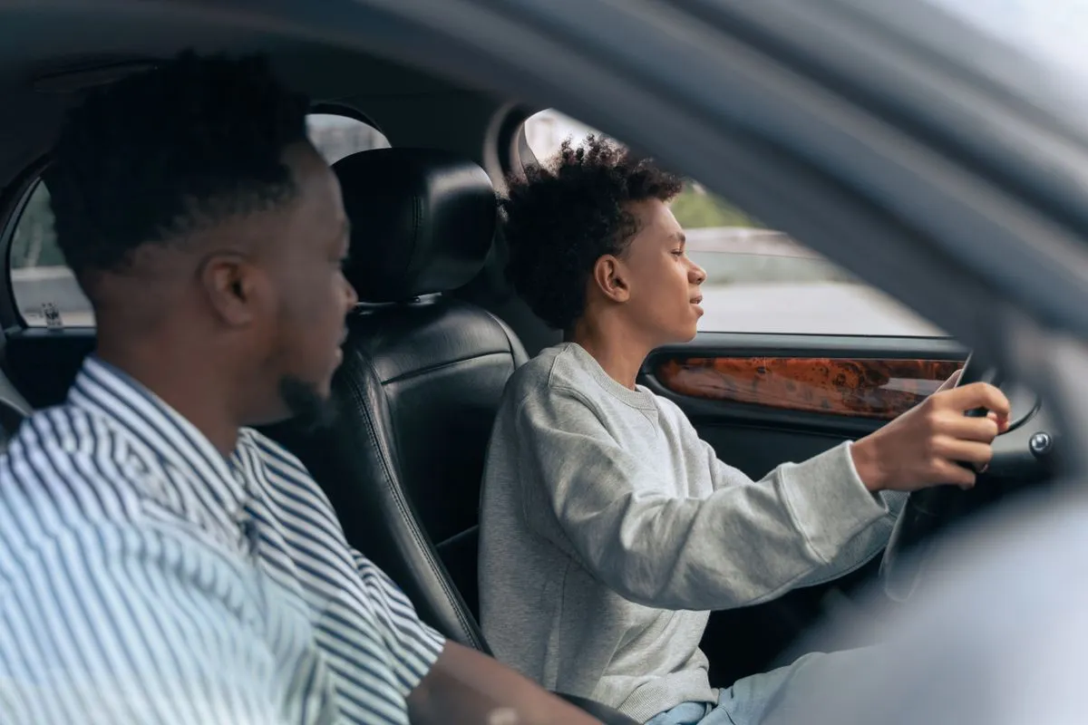 Parent who is co-signing a car loan teaching their child to drive
