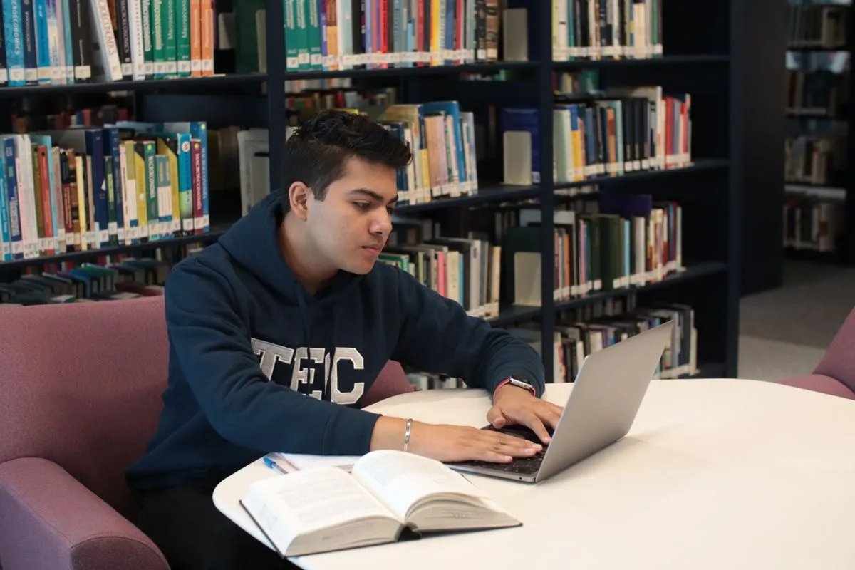 Student applying for a student loan on a laptop in the library