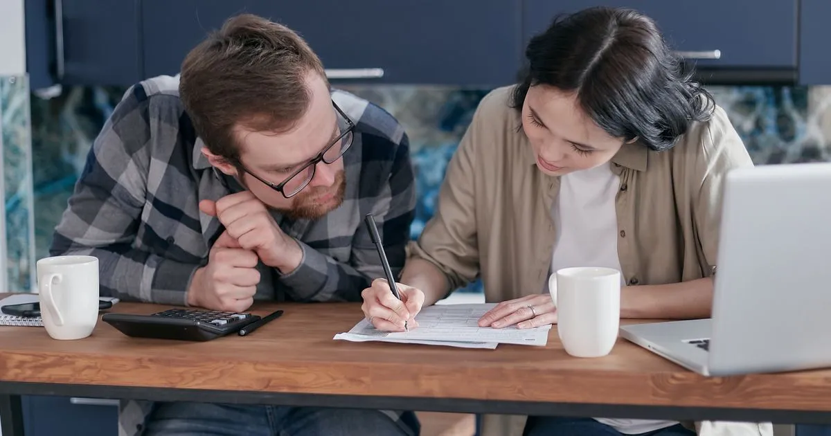 Couple budgeting a $1500 loan soft credit check repayment at their kitchen table in Canada