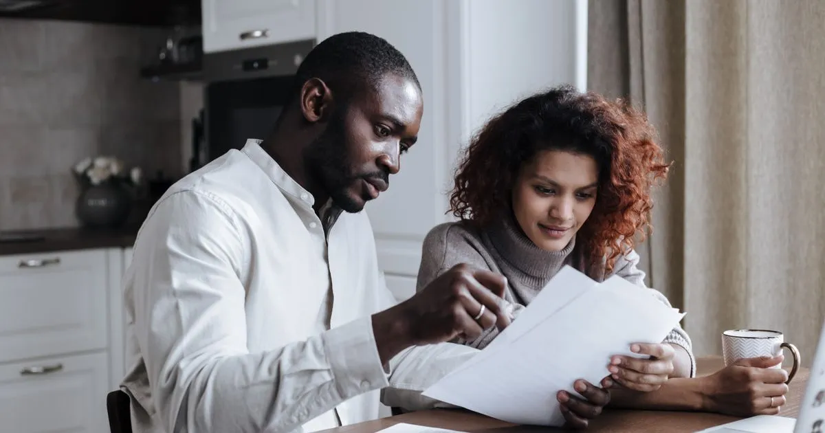 Saskatoon couple comparing personal loan offers and paperwork at their kitchen table