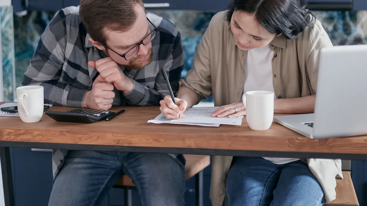 Couple at a kitchen table checking what income personal loans need beside rent and bills
