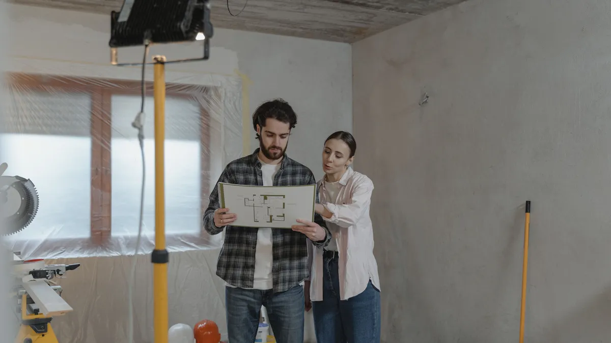 Couple reviewing a floor plan in a room under renovation, a common use of personal loans