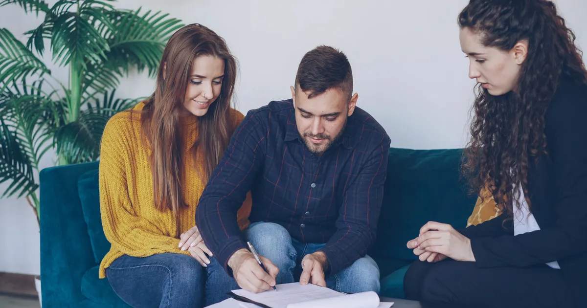 Couple signing a personal loans agreement with an advisor